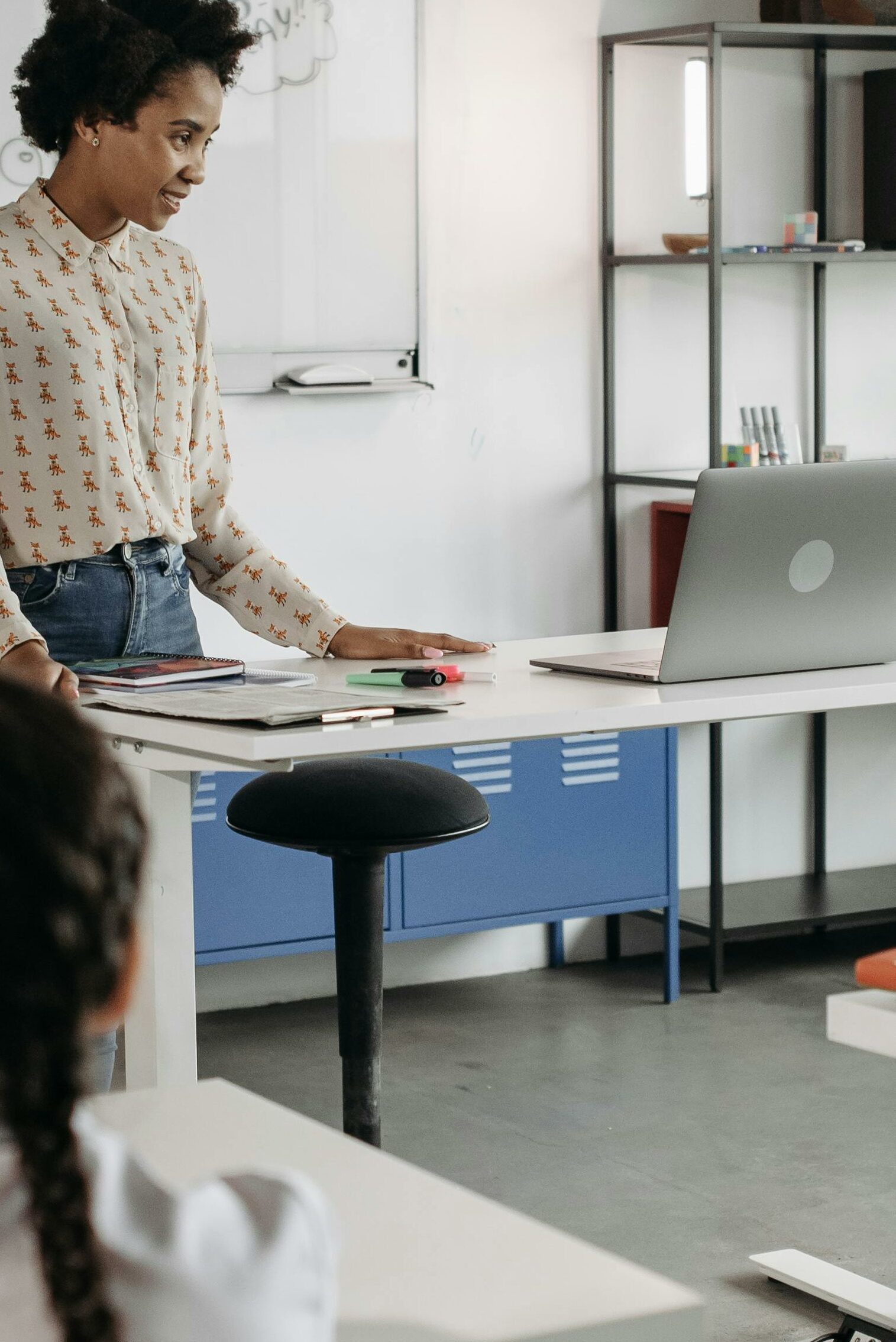 A teacher in a science classroom with her 14 inch silver laptop