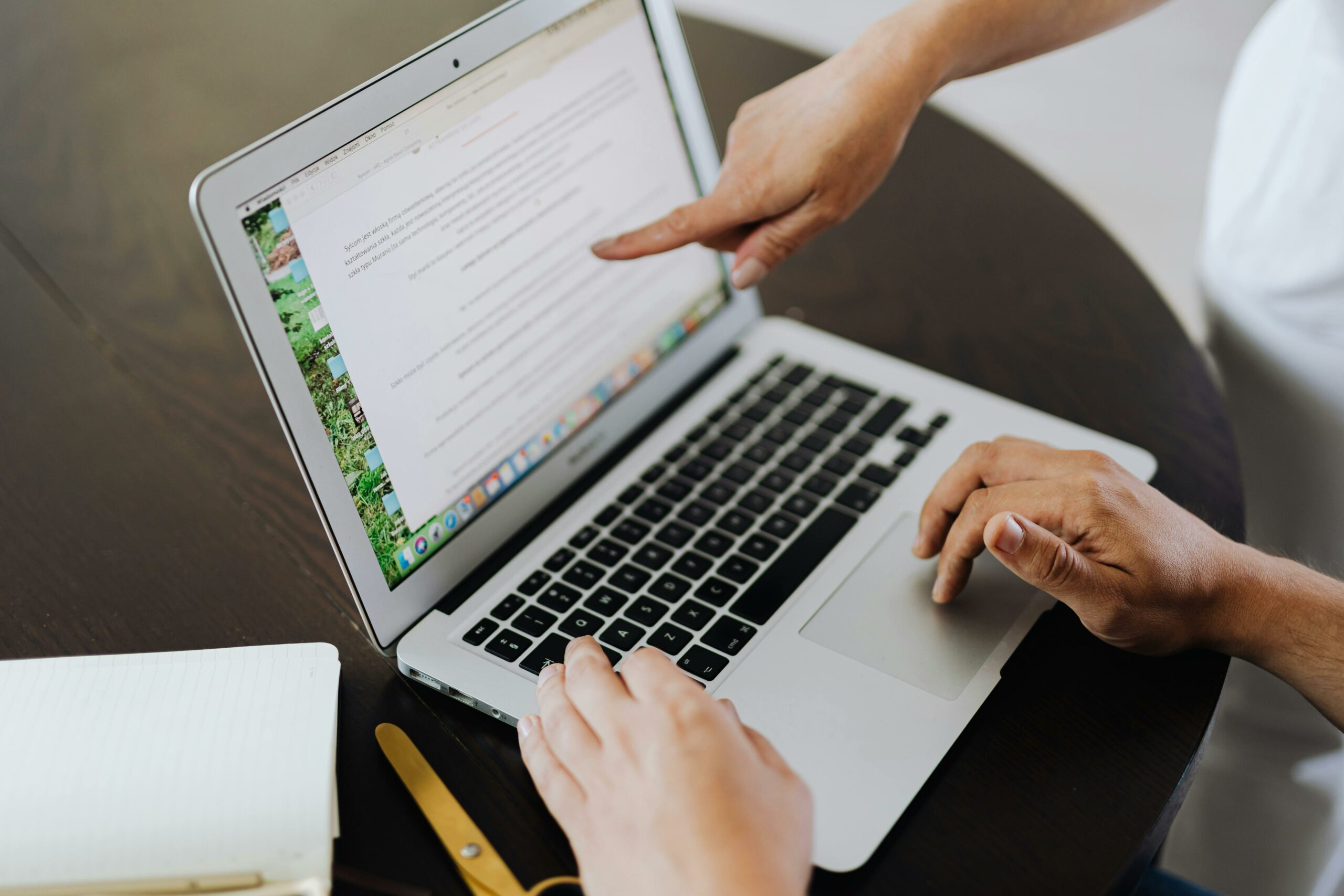 Teacher in a UK secondary school guiding a teacher assistant on a presentation using a silver chrome book