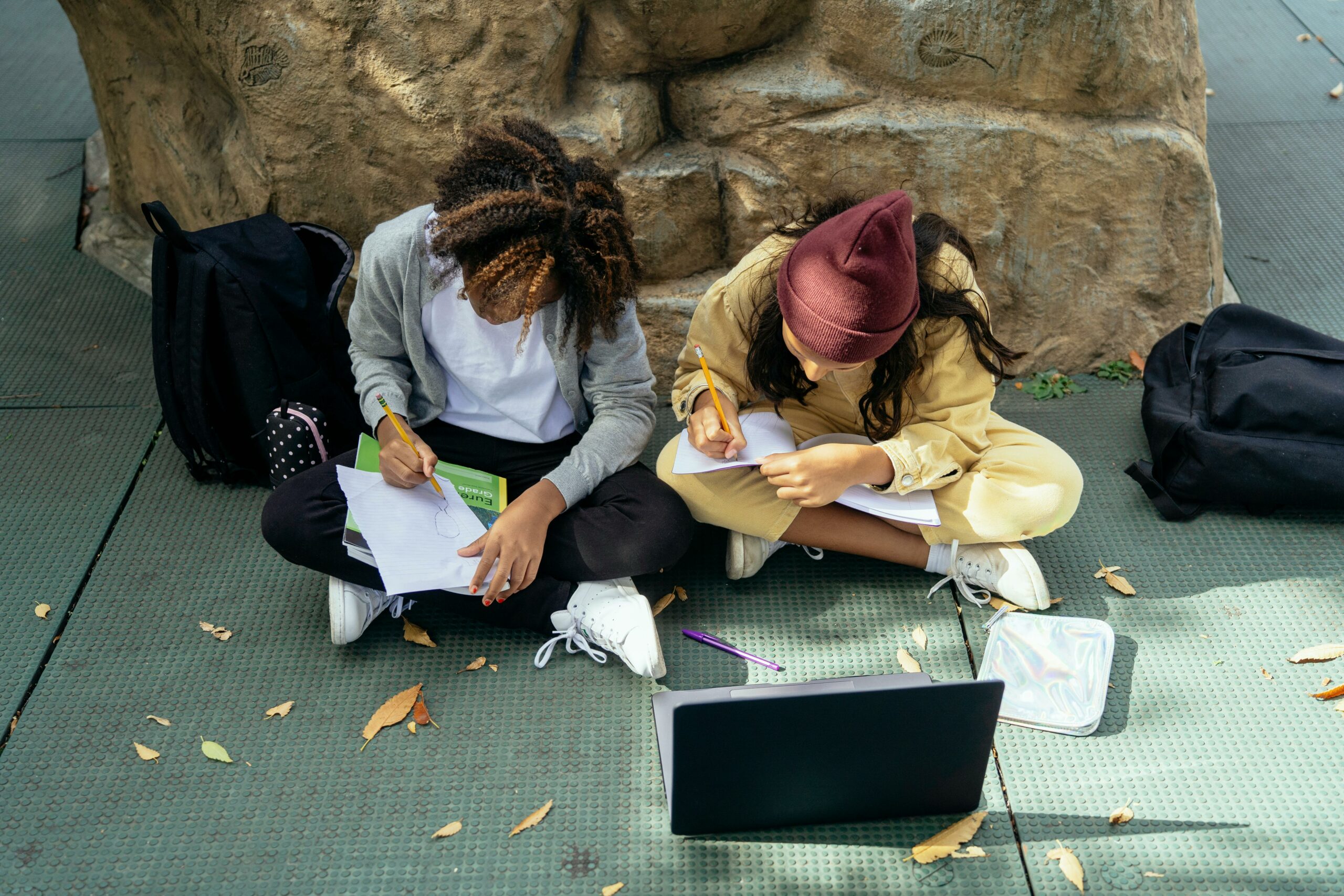 Two secondary students sitting near the Victoria and Albert Museum with Chromebook laptop for a short project